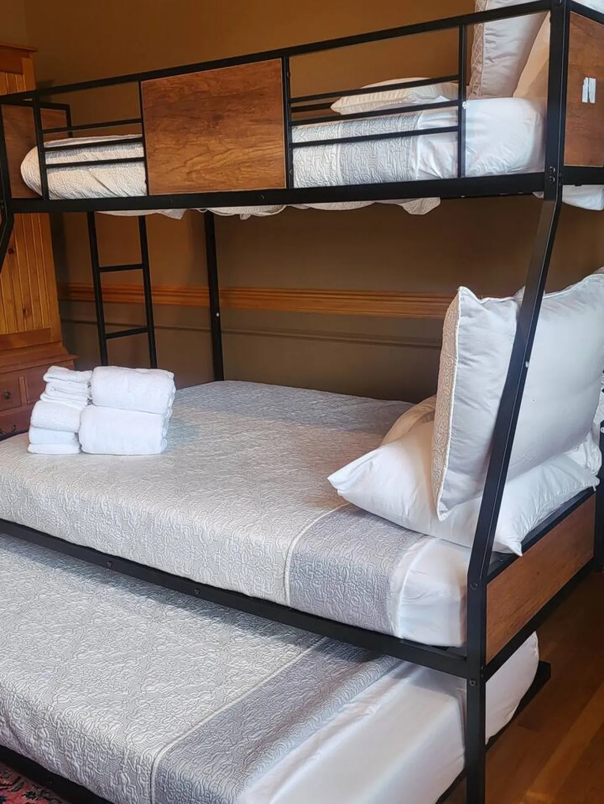 A cheerful bedroom with a sturdy bunk bed, neatly arranged towels, and decorative pillows. The setup suggests a family-friendly environment that is both comfortable and practical, ideal for multiple guests or children.