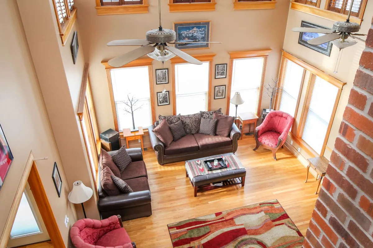 A comfortable living space with multiple sofas arranged for group seating, a central coffee table, wall art, and large windows letting in ample natural light. The overall mood is cozy and inviting, perfect for group activities or quiet mornings.